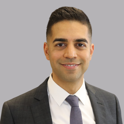 Dr. Farhad Peerani smiling on a grey background