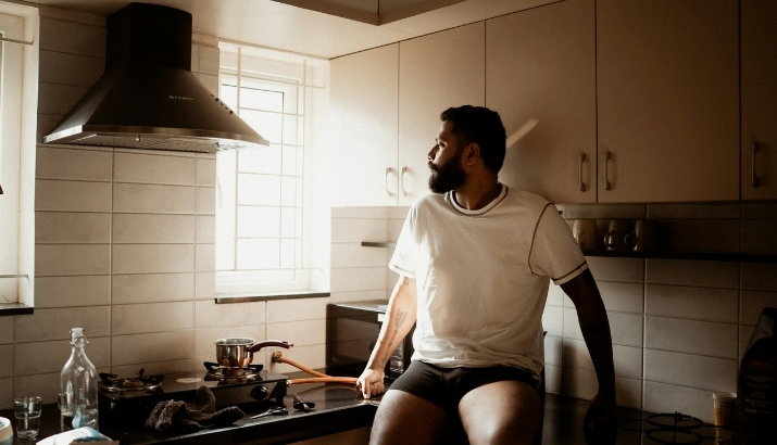 A person living with IBD sitting on their kitchen counter and thinking
