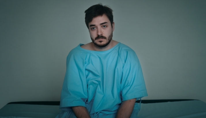 A person living with IBD sitting on a hospital bed awaiting their gastroenterologist