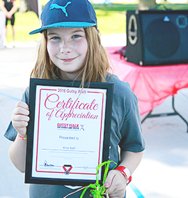 Young volunteer holding up her Gutsy Walk Certificate of Appreciation