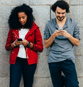 Two young people looking into Crohn's and Colitis Canada's peer supports from their mobile devices