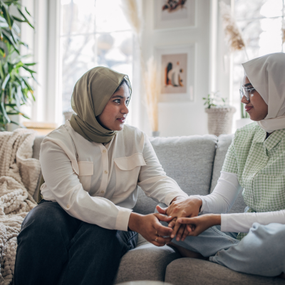 two women sitting on a couch offering support.