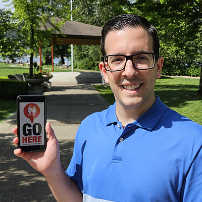 Matthew Sebastiani holding a mobile device with the GoHere app displayed