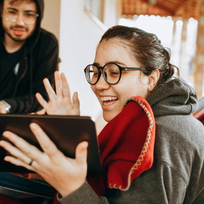 A young man and young woman are sitting looking at a tablet