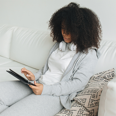 young woman sitting on couch using tablet